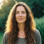 Mulher com cabelo longo, saudável e brilhante sorrindo ao sol em um ambiente natural, representando os benefícios da biotina.